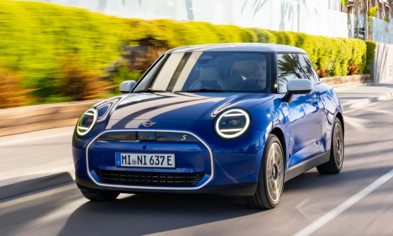 Novo Mini Cooper SE elétrico azul andando com fundo florido