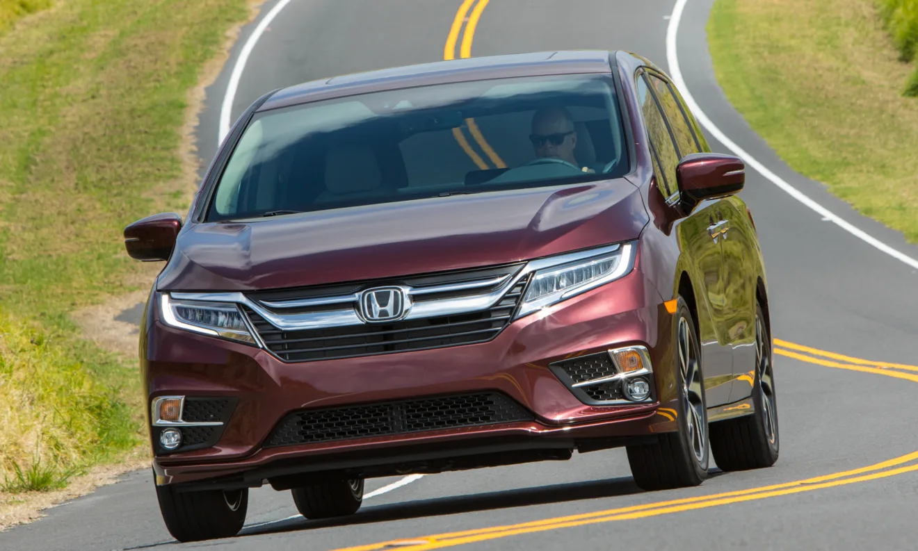 Honda Odyssey vinho, visto de frente e andando em rodovia